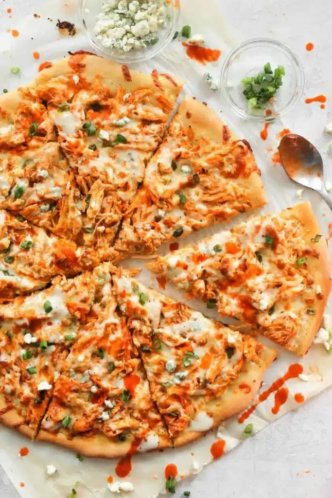 Buffalo Chicken Pizza with melted cheese and fresh herbs on a wooden board